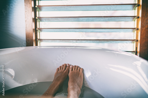 Bath soaking feet woman relaxing in hot bathtub water relaxation wellness foot therapy.