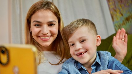 Beautiful mom and son making selfie at home. Happy family having a facetime video call. Unity, connection, technology concept