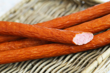 Traditional Polish smoked sausages called kabanos on wicker surface closeup