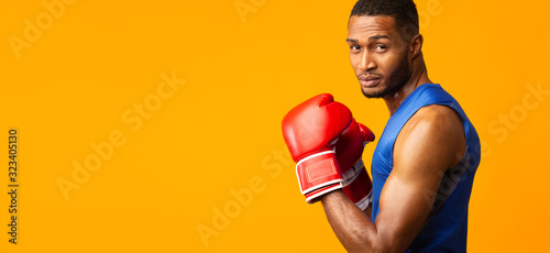 Leinwand Poster Portrait of confident black man wearing red boxing gloves