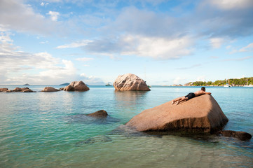 Wall Mural - Man resting on granite boulder landscape in the Seychelles