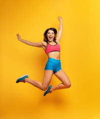 Sport woman jumps on a yellow background. Happy and joyful expression.