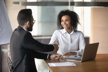 Poster - African and arab businesspeople seated at desk in boardroom handshaking