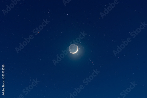 Fotomural Waxing crescent moon, earthshine and starry night sky
