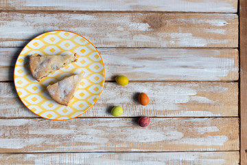 Wall Mural - Easter cake slices with dried apricots, raisins, nuts on plate and colorful quail eggs on wooden background