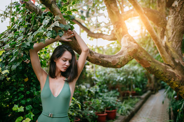 woman in green swimsuit, good-looking lady merges with wildlife and looks organically around plants and trees. beautiful female spending vacation in tropical rainforest. nature, wildlife and human