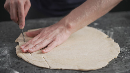 Wall Mural - man cutting flat dough with knife