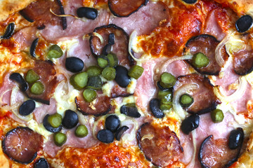 Wall Mural - pizza texture background with hum, sausage,cucumber, olives onion and cheese close up photo top view