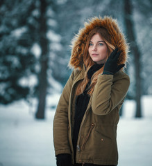 Portrait of beautiful caucasian young woman in the snow forest in cold winter day