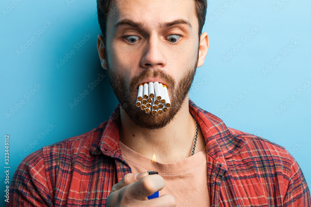 surprised caucasian man with pack of cigarettes in mouth, young male  wearing red casual shirt hold