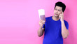 Travel concept. Studio portrait of pretty young Asian man holding passport  and thinking about something. Isolated on isolated on pink background in studio With copy space.