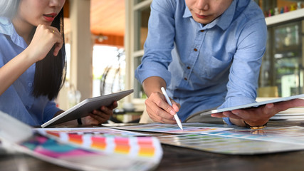 Leinwandbilder - Cropped image of young graphic designer team holding/using a stylus pen and computer tablet while planning/brainstorming/discussing about their new project design at the modern meeting table.