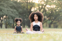 African American Little Girl Sitting On The Roll Mat Practicing Meditate Yoga In The Park Outdoor