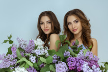 Studio Fashion Portrait Photo Of Two Twins Women With A Bouquet Of Spring Flowers