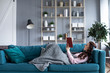 Happy woman with a book in her hands resting on a cozy sofa at home.