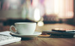 © Lek - Closeup white cup of coffee with smartphone, notebook  on wooden table in cafe. with vintage light, blurred and bokeh background