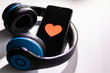 Schwarzes Smartphone mit Herz zum Valentinstag und blauem Funkkopfhörer zeigt Liebe zur Musik und mobilen Musikgenuss dank Musikstreaming und Audiobooks unterwegs immer dabei
