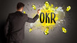 © ra2 studio - businessman drawing colorful light bulb with OKR abbreviation, new technology idea concept