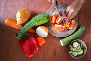 Wall Mural - Chopping fresh vegetables on wooden table showing concept of vegan lifestyle, healthy diet and clean living