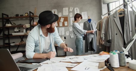 Wall Mural - A hipster tailor couple is working together at their office, designing their new fashionable clothes collection - small family business concept 4k footage