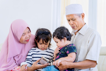 Wall Mural - Elderly muslim parents lapping their grandchildren