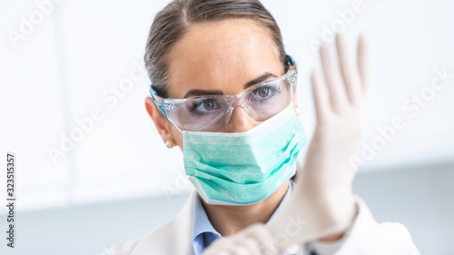 Fotografía Doctor woman surgeon specialist in sterile clothing putting on surgical gloves