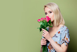 Fototapeta Tulipany - Beautiful blonde woman in dress with roses on green background