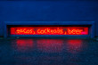 red glowing neon sign for tacos, cocktails and beer with reflection