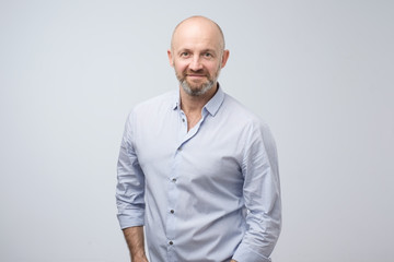 Confident mature man with beard looking at camera with serious face. Studio shot