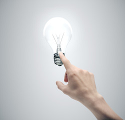 Aufkleber - Hand pushing light bulb on gray background.