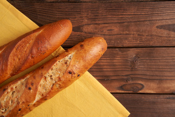 two crispy french baguettes lie on an old wooden table with free space for text