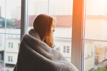Thoughtful Calm Pensive Young Woman Looking Through The Window At Home Wrapped In Warm Comfy Blanket