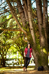 Wall Mural - a young man with long hair,rock style, stands near a tree