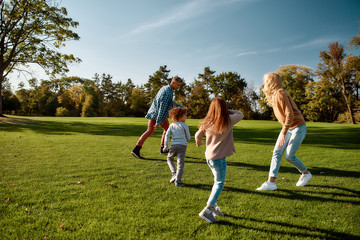 Resting together. Excited family running outdoors on a sunny day