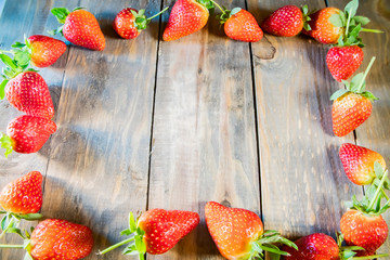 Wall Mural - frame from strawberry berries close up on a wood background