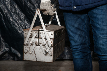 Taking tools from the tool box. The man holds a metal box in his hand, opens and gets the tools for work. The concept of physical work, repairs.