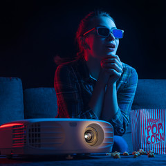 Wall Mural - Watching movies in a movie theater, cinema with a projector. 3D glasses and popcorn. Creative light. Square photo.