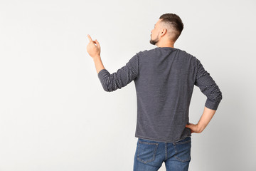 Wall Mural - Man pointing at something on light background