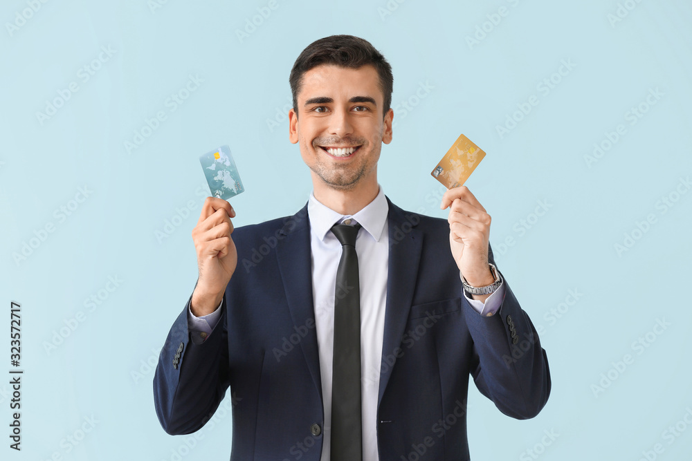 Male bank manager with credit cards on light background