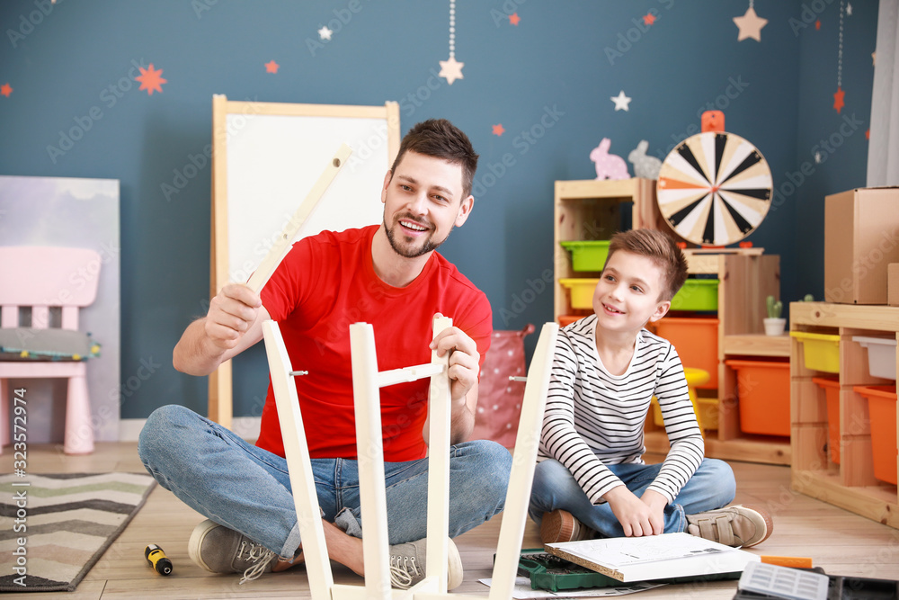 Father and his little son assembling furniture at home