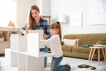 Wall Mural - Mother and her little daughter assembling furniture at home