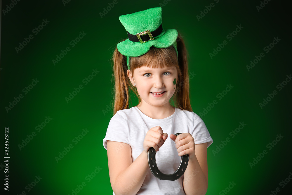 Funny little girl with horseshoe on dark background. St. Patrick's Day celebration