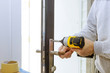 © ungvar - Install the door handle with a lock, Carpenter tighten the screw, using an electric drill screwdriver,