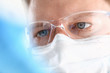 © H_Ko - A portrait of a young surgeon chemist doctor looks at a container with a blue liquid and a mask is fought with viruses and a vaccine for vaccines against diseases.