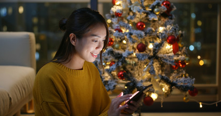 Canvas Print - Woman use of mobile phone with christmas tree decoration at home