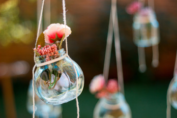 Decoration glass jar with flowers hanging with blur garden background. Soft focus