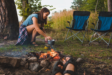 Wall Mural - couple resting near bonfire. woman cooking outdoors on fire