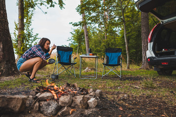 Wall Mural - couple resting near bonfire. woman cooking outdoors on fire