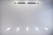 look up on suspended ceiling with halogen spots lamps and drywall construction in empty room in apartment or house. Stretch ceiling white and complex shape.