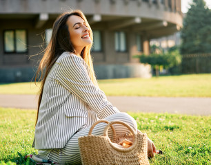 Wall Mural - Young stylish woman relax sitting on a grass in city park